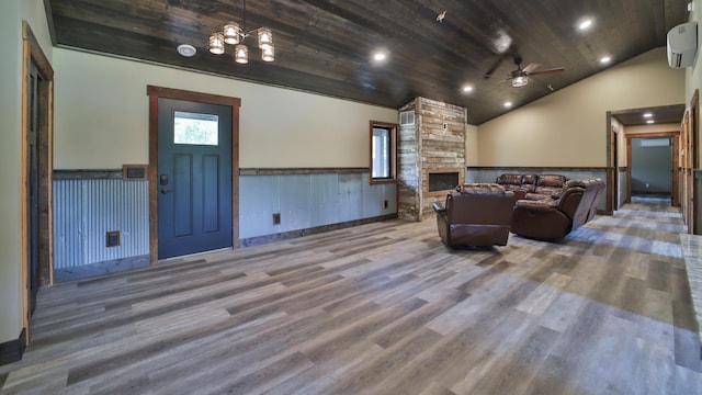 living room with wood ceiling, ceiling fan with notable chandelier, a fireplace, hardwood / wood-style floors, and a wall mounted AC