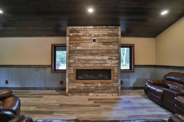 living room featuring a stone fireplace, hardwood / wood-style flooring, wood ceiling, and crown molding