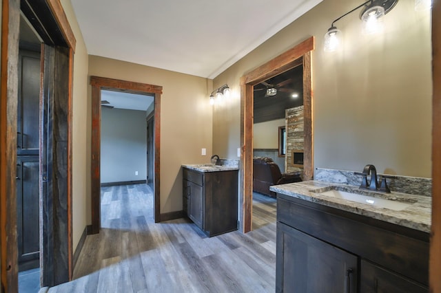 bathroom featuring a stone fireplace, vanity, and hardwood / wood-style floors