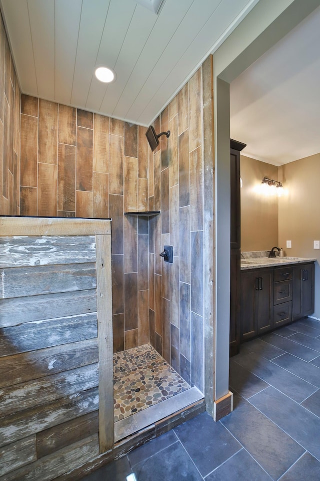 bathroom with a tile shower, tile patterned flooring, and vanity