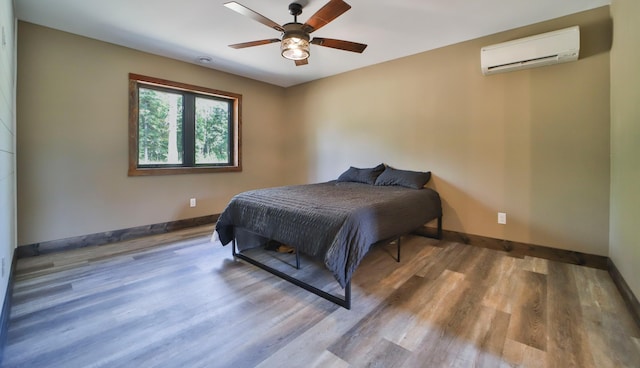 bedroom featuring ceiling fan, hardwood / wood-style flooring, and a wall mounted AC