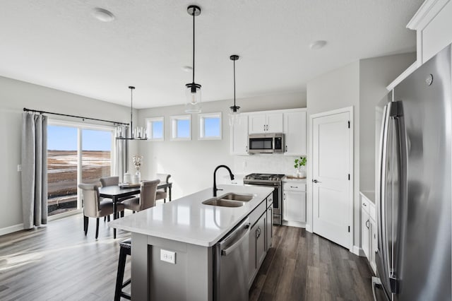 kitchen with hanging light fixtures, sink, a center island with sink, white cabinetry, and stainless steel appliances