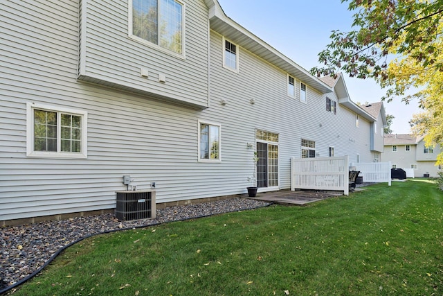 back of property featuring central air condition unit and a lawn