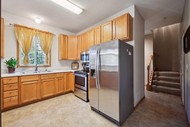 kitchen featuring appliances with stainless steel finishes, sink, and a textured ceiling