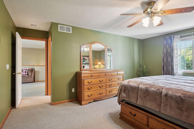 bedroom featuring light colored carpet, a textured ceiling, and ceiling fan