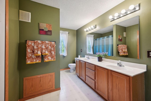 bathroom featuring vanity, toilet, and a textured ceiling