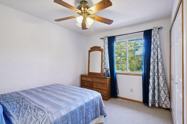 bedroom featuring light carpet, a closet, a textured ceiling, and ceiling fan