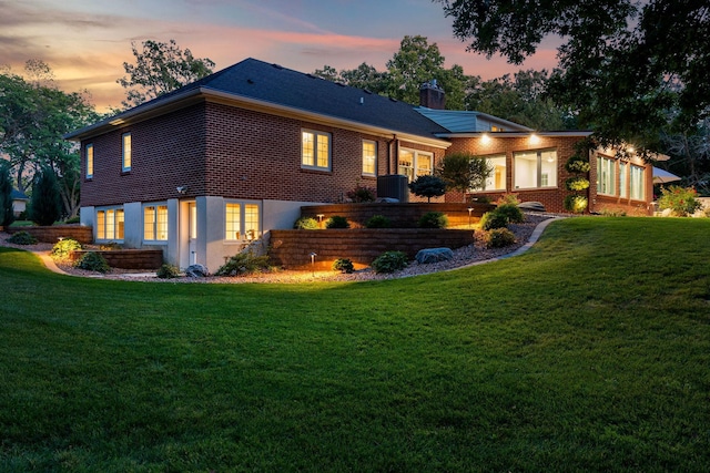 301 22nd St NW, Austin, MN 55912 - back of house at dusk with a yard, brick siding, and a chimney