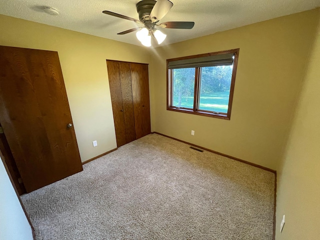 unfurnished bedroom with a closet, carpet, ceiling fan, and a textured ceiling