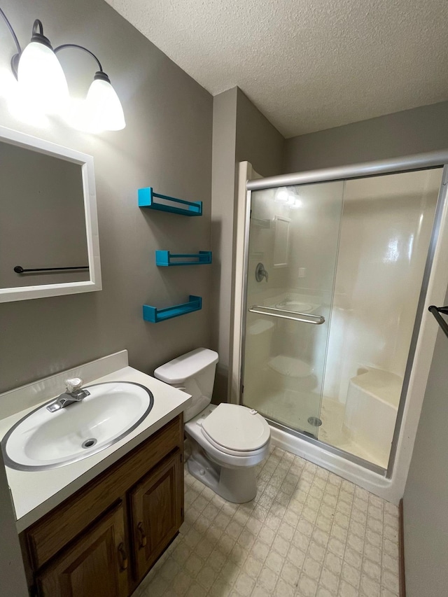 bathroom with vanity, a textured ceiling, toilet, and a shower with door