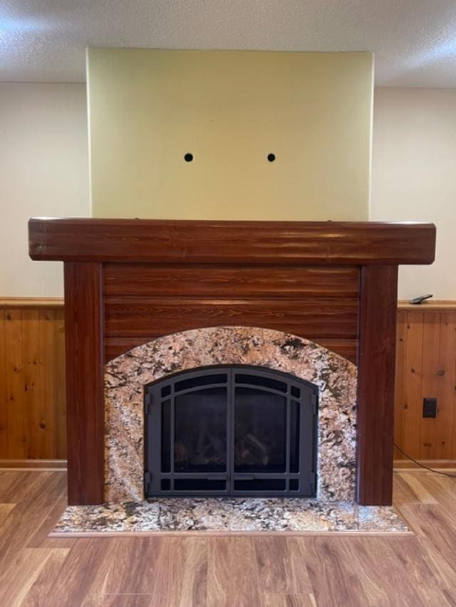 details featuring hardwood / wood-style flooring, wooden walls, a textured ceiling, and a high end fireplace