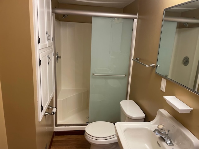 bathroom with hardwood / wood-style flooring, toilet, sink, and an enclosed shower