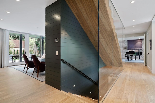 hallway featuring light wood-type flooring and wood walls