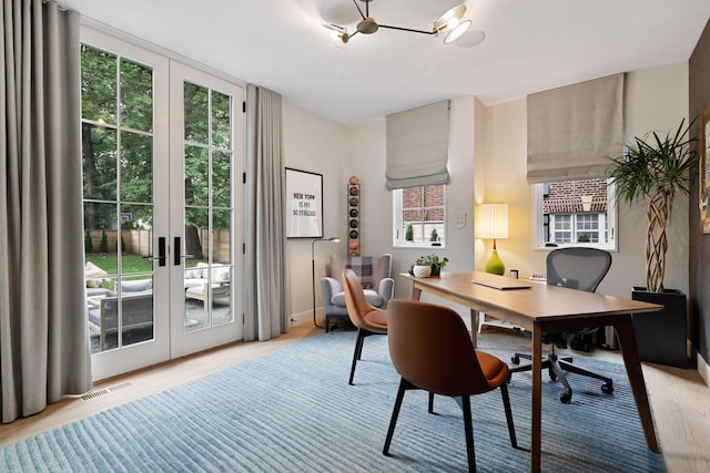 office space featuring french doors, light hardwood / wood-style flooring, and a healthy amount of sunlight