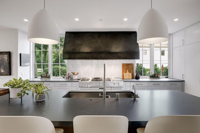 kitchen with ventilation hood, pendant lighting, decorative backsplash, and a healthy amount of sunlight