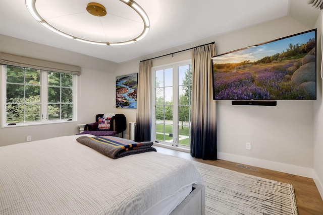 bedroom with access to outside, light hardwood / wood-style flooring, and multiple windows