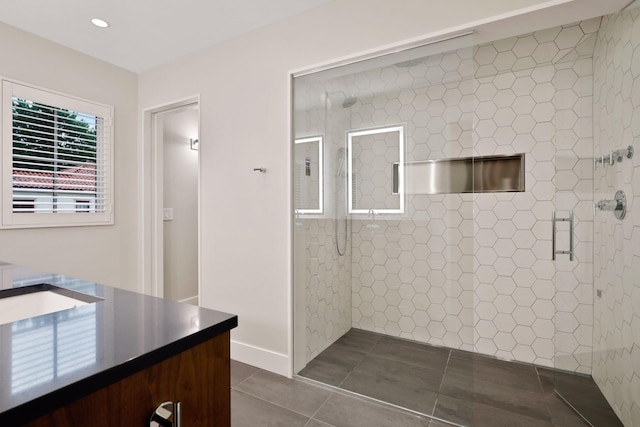 bathroom with tile patterned flooring, vanity, and tiled shower