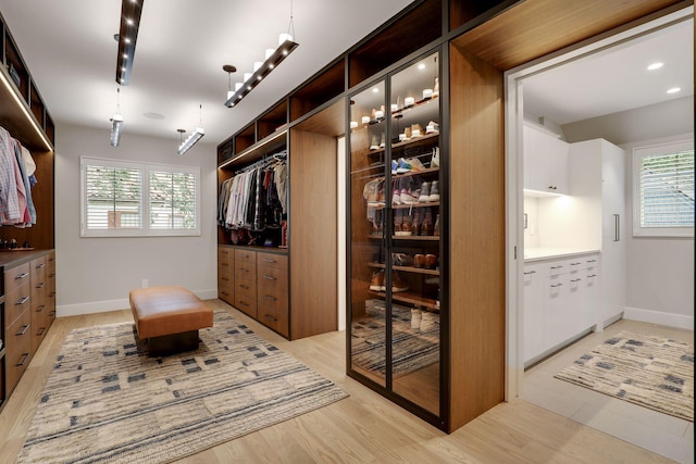 walk in closet with light hardwood / wood-style flooring