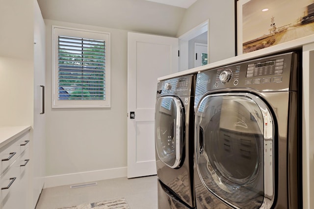 laundry room featuring light tile patterned flooring, washing machine and clothes dryer, and cabinets