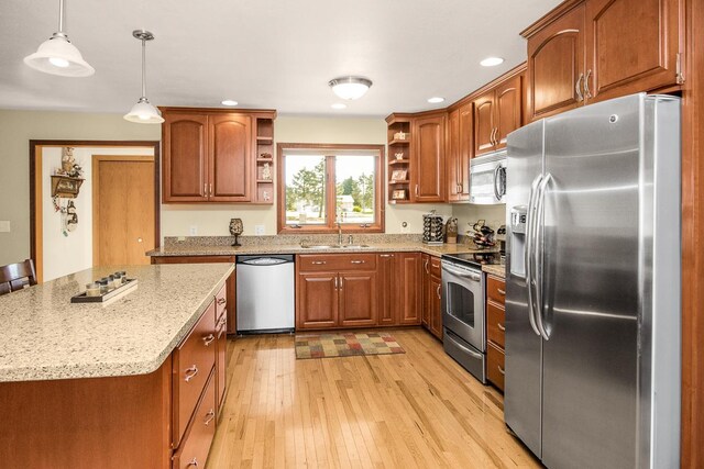 kitchen featuring pendant lighting, light hardwood / wood-style flooring, light stone counters, sink, and stainless steel appliances