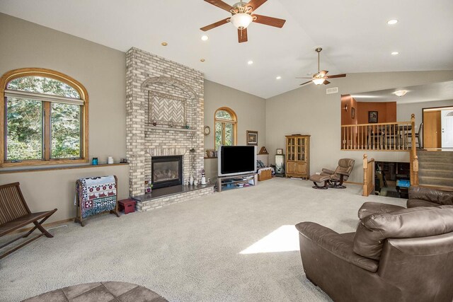 living room featuring ceiling fan, lofted ceiling, a brick fireplace, and carpet