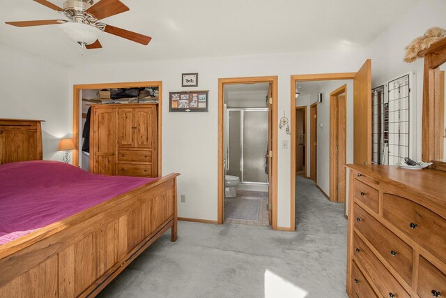 bedroom with ceiling fan, light colored carpet, and ensuite bath