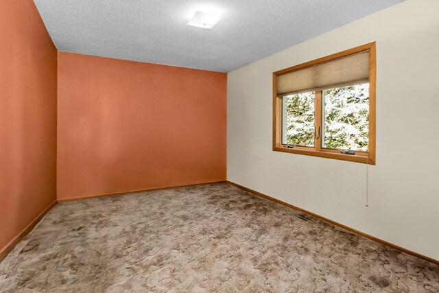 carpeted empty room with a textured ceiling