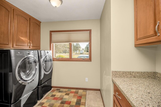 clothes washing area with light tile patterned flooring, separate washer and dryer, and cabinets