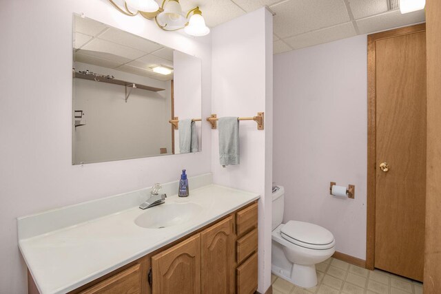 bathroom featuring a drop ceiling, vanity, and toilet