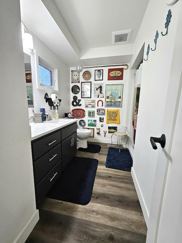 bathroom featuring hardwood / wood-style floors, walk in shower, vanity, and toilet