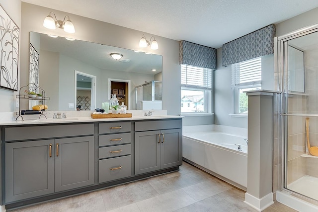 bathroom featuring vanity, plus walk in shower, a textured ceiling, and tile patterned floors