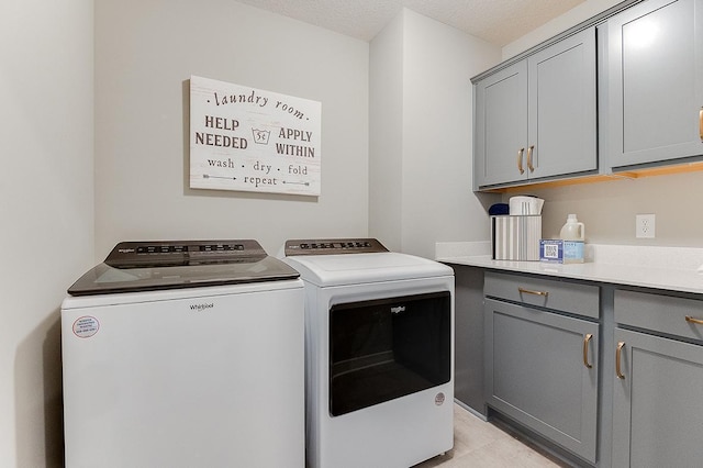 clothes washing area with cabinets, a textured ceiling, and separate washer and dryer