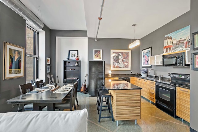 kitchen featuring a center island, sink, hanging light fixtures, a kitchen breakfast bar, and black appliances