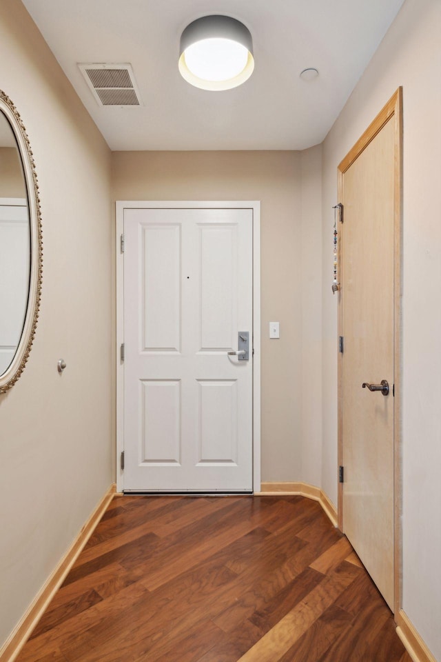 entryway with dark wood finished floors, visible vents, and baseboards