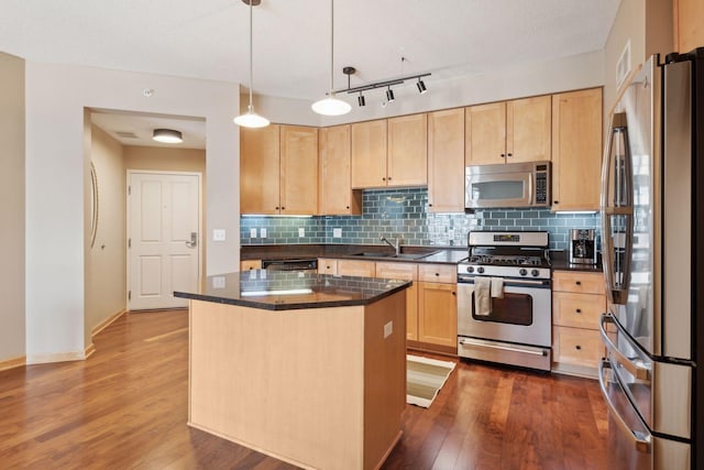 kitchen featuring light brown cabinetry, appliances with stainless steel finishes, dark countertops, and a kitchen island