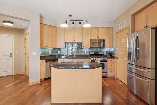 kitchen featuring light brown cabinetry, appliances with stainless steel finishes, and a center island