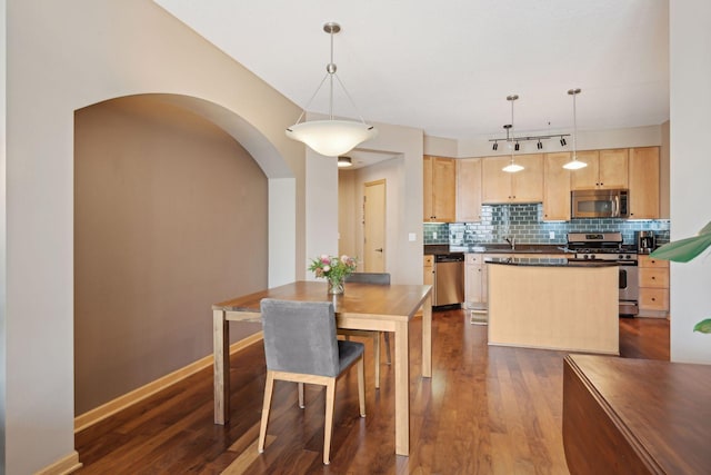 dining room featuring dark wood-type flooring, arched walkways, and baseboards