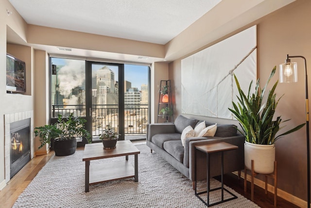 living room with light wood-style floors, a tile fireplace, visible vents, and a city view