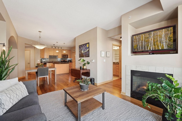 living area featuring light wood-style floors, baseboards, and a tiled fireplace