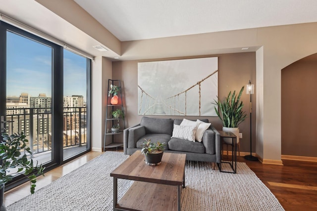 living area with baseboards, arched walkways, visible vents, wood finished floors, and a view of city