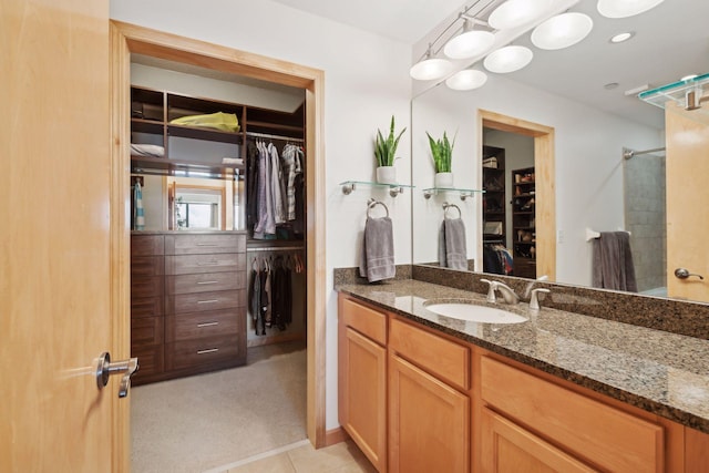 full bathroom featuring tile patterned flooring, a spacious closet, walk in shower, and vanity