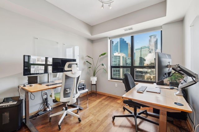 office featuring visible vents, baseboards, and wood finished floors