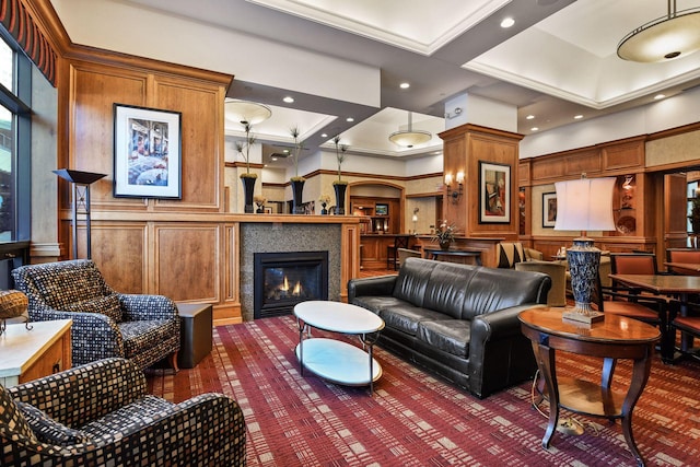 living room with recessed lighting, a decorative wall, a towering ceiling, ornamental molding, and a glass covered fireplace