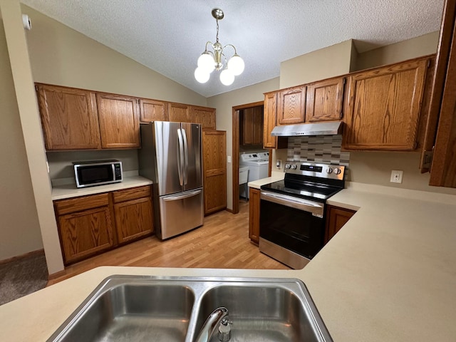 kitchen featuring appliances with stainless steel finishes, hanging light fixtures, light hardwood / wood-style floors, independent washer and dryer, and a notable chandelier