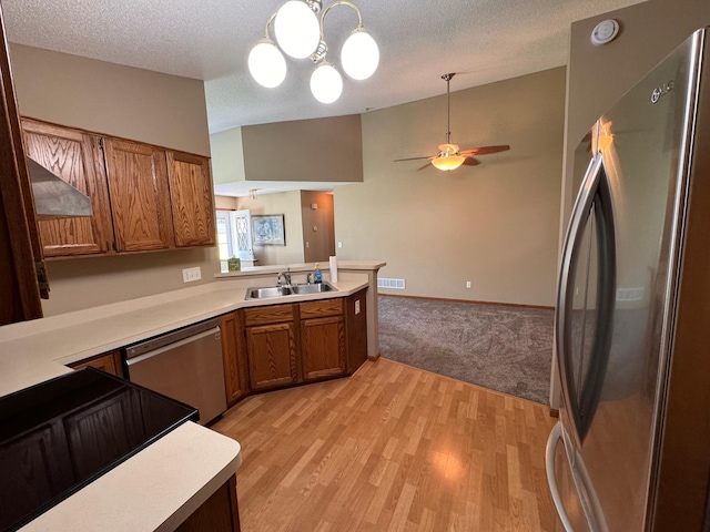 kitchen featuring appliances with stainless steel finishes, kitchen peninsula, a textured ceiling, light hardwood / wood-style flooring, and sink