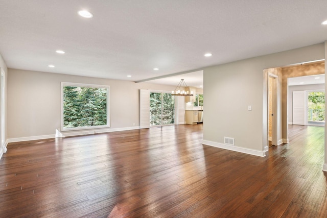 spare room featuring dark hardwood / wood-style flooring and a notable chandelier