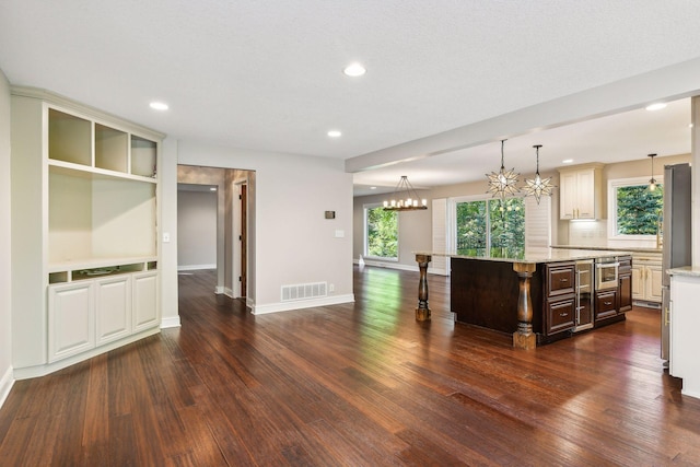 kitchen featuring a center island, dark hardwood / wood-style floors, light stone counters, and a healthy amount of sunlight