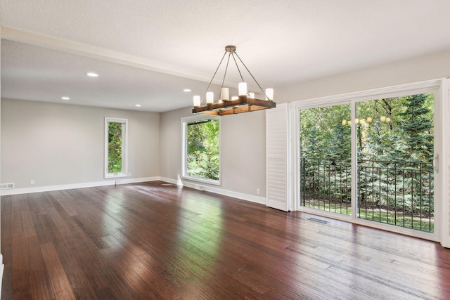 spare room with a textured ceiling and dark hardwood / wood-style floors