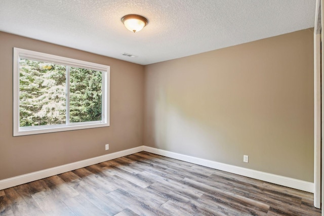 spare room featuring a textured ceiling and hardwood / wood-style flooring