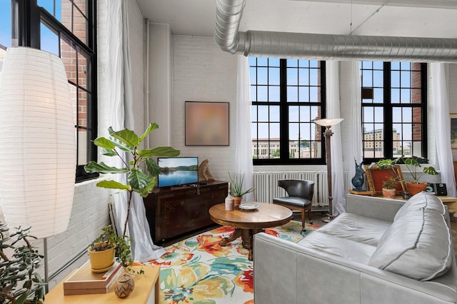 living area featuring brick wall, radiator heating unit, and plenty of natural light